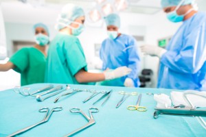 Hospital - surgery team in the operating room or Op of a clinic operating on a patient, perhaps it's an emergency a assistant holding a cotton swap forceps